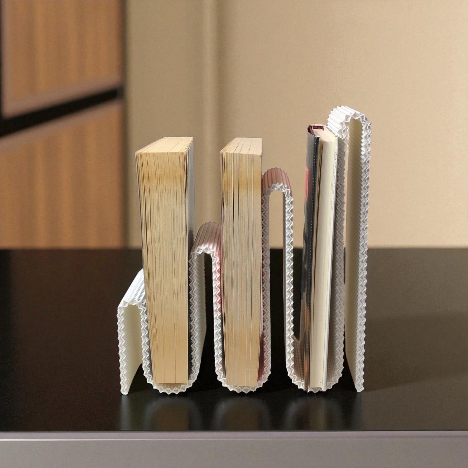 Modern wavy book stand in textured white, holding two books upright; perfect for organizing books, magazines, or vinyls on a desk, shelf, or reading nook