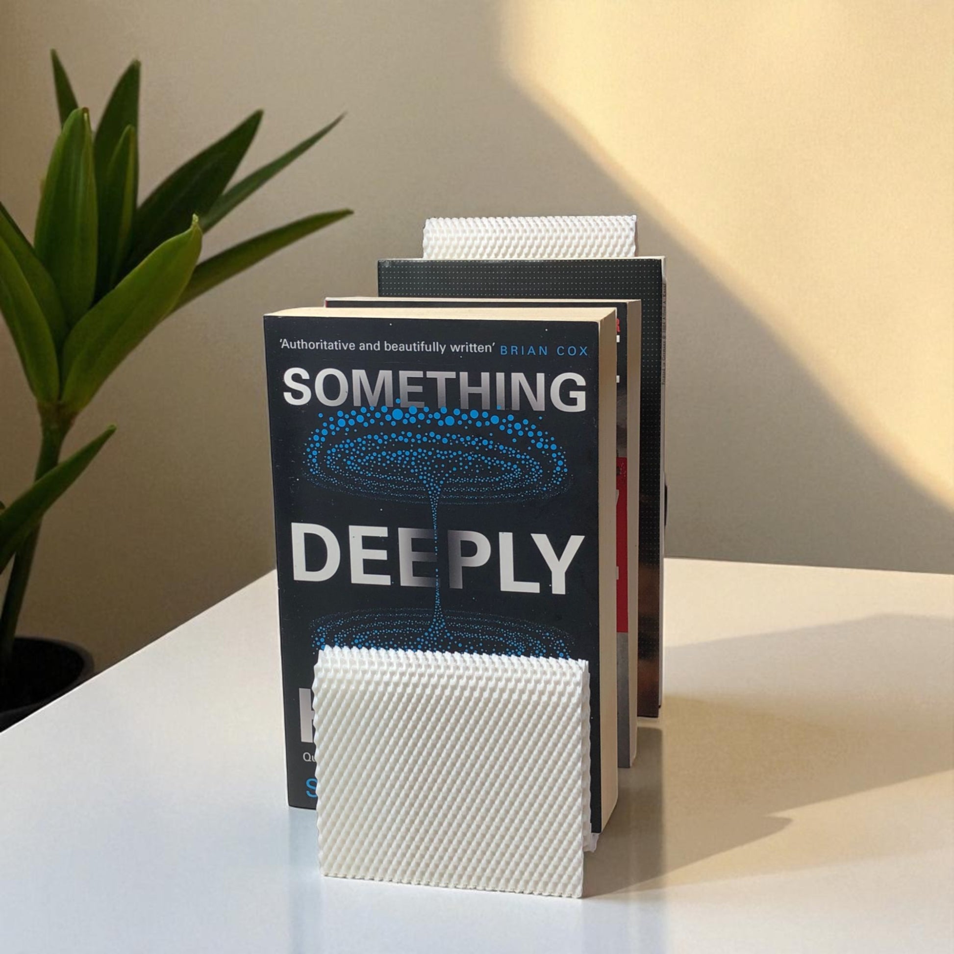 Modern wavy book stand in textured white, holding two books upright; perfect for organizing books, magazines, or vinyls on a desk, shelf, or reading nook