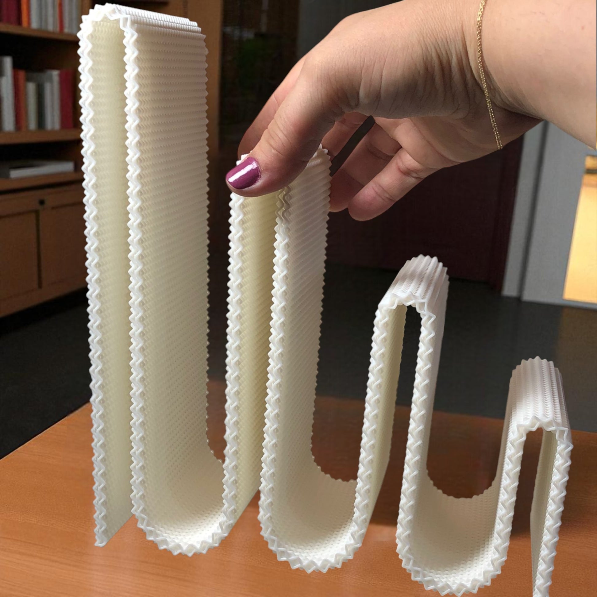 Modern wavy book stand in textured white, holding two books upright; perfect for organizing books, magazines, or vinyls on a desk, shelf, or reading nook