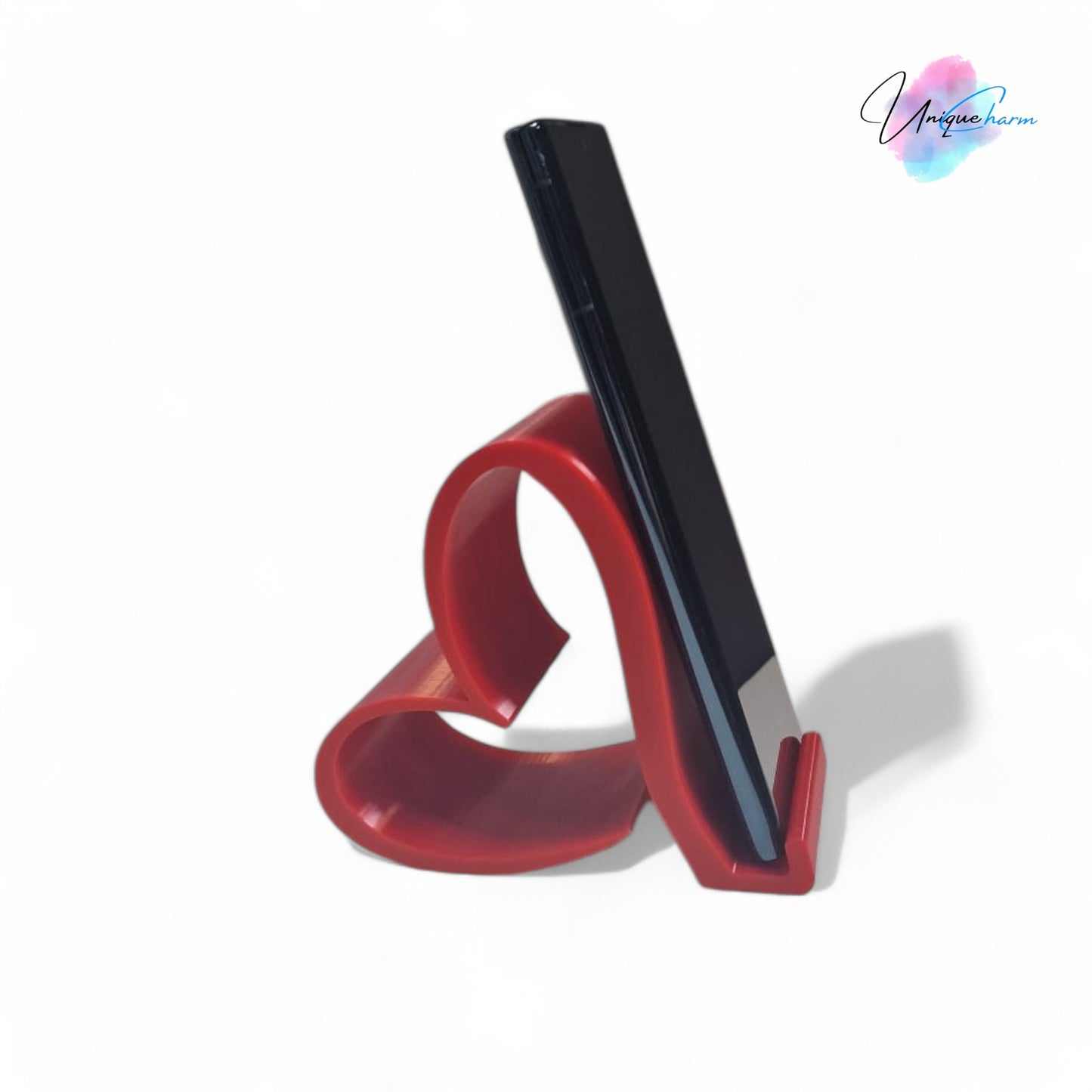 heart-shaped universal phone and kindle holder in an elegant design, securely holding a smartphone on a desk. stylish and versatile stand suitable for all phones, kindles, and small tablets, perfect for hands-free viewing