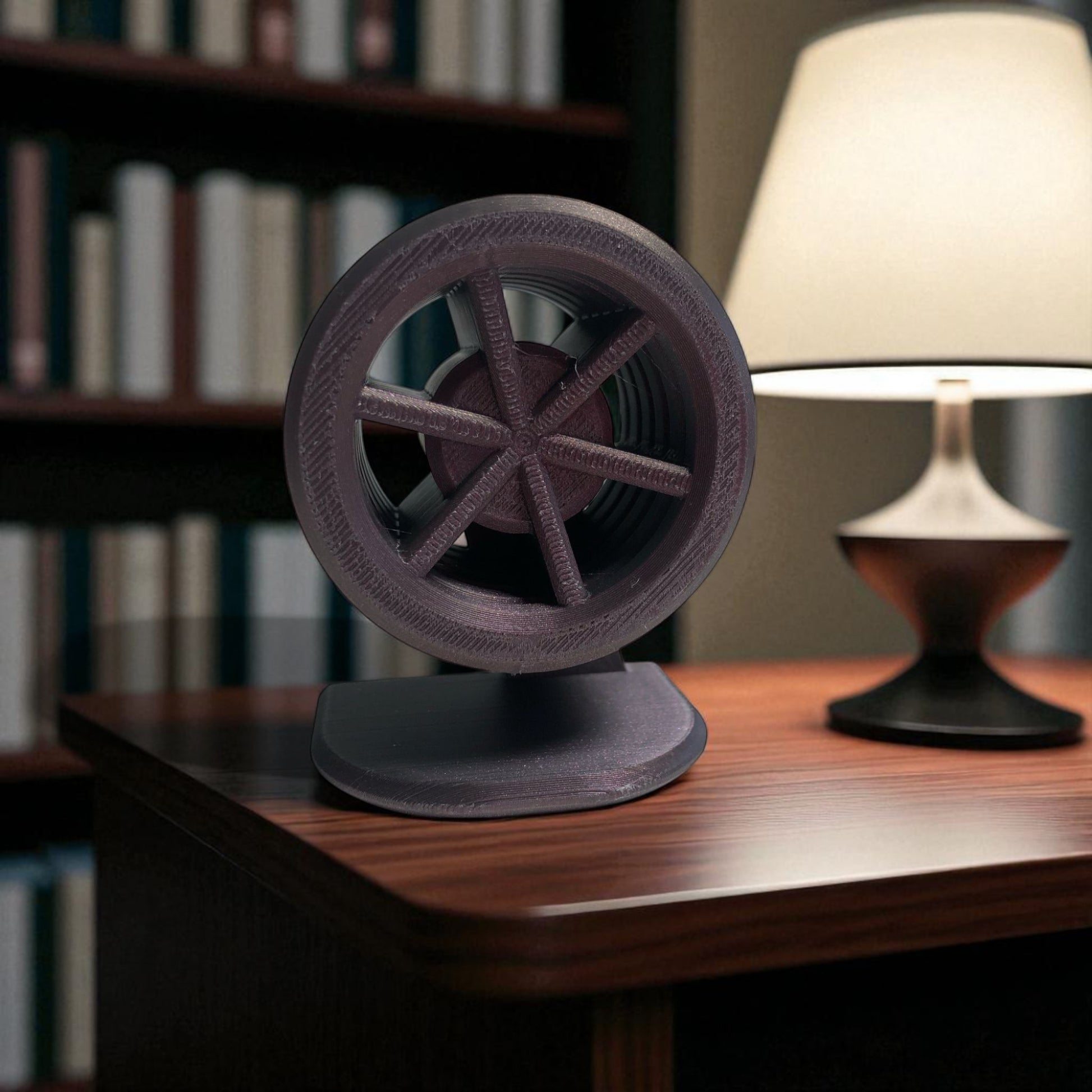 Decorative object resembling a film reel on a wooden surface with a blurred bookshelf and lamp in the background.