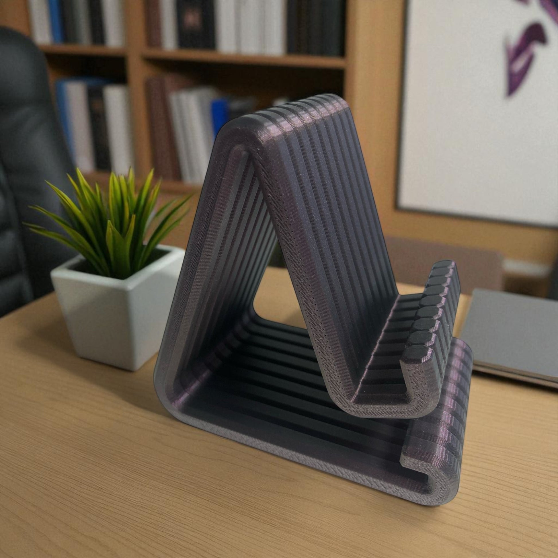 Gray desk riser on a wooden desk with a plant and books in the background