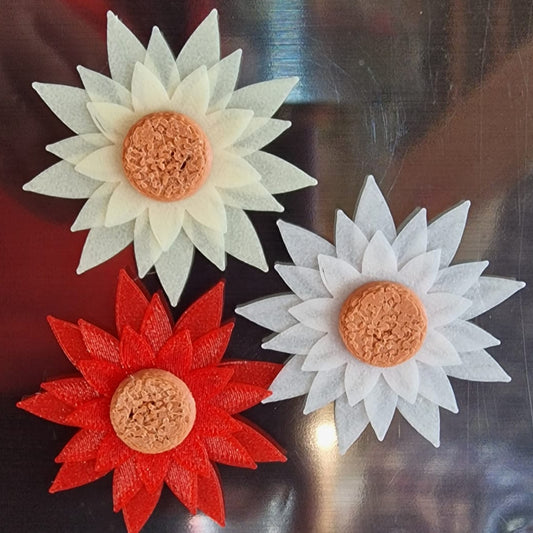 Two flower-shaped earrings, one red and one white, on a reflective surface.