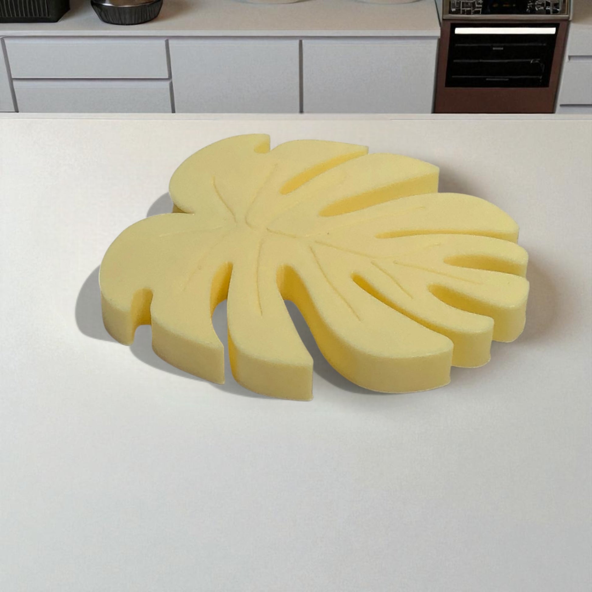 Yellow leaf-shaped kitchen sponge on a white countertop