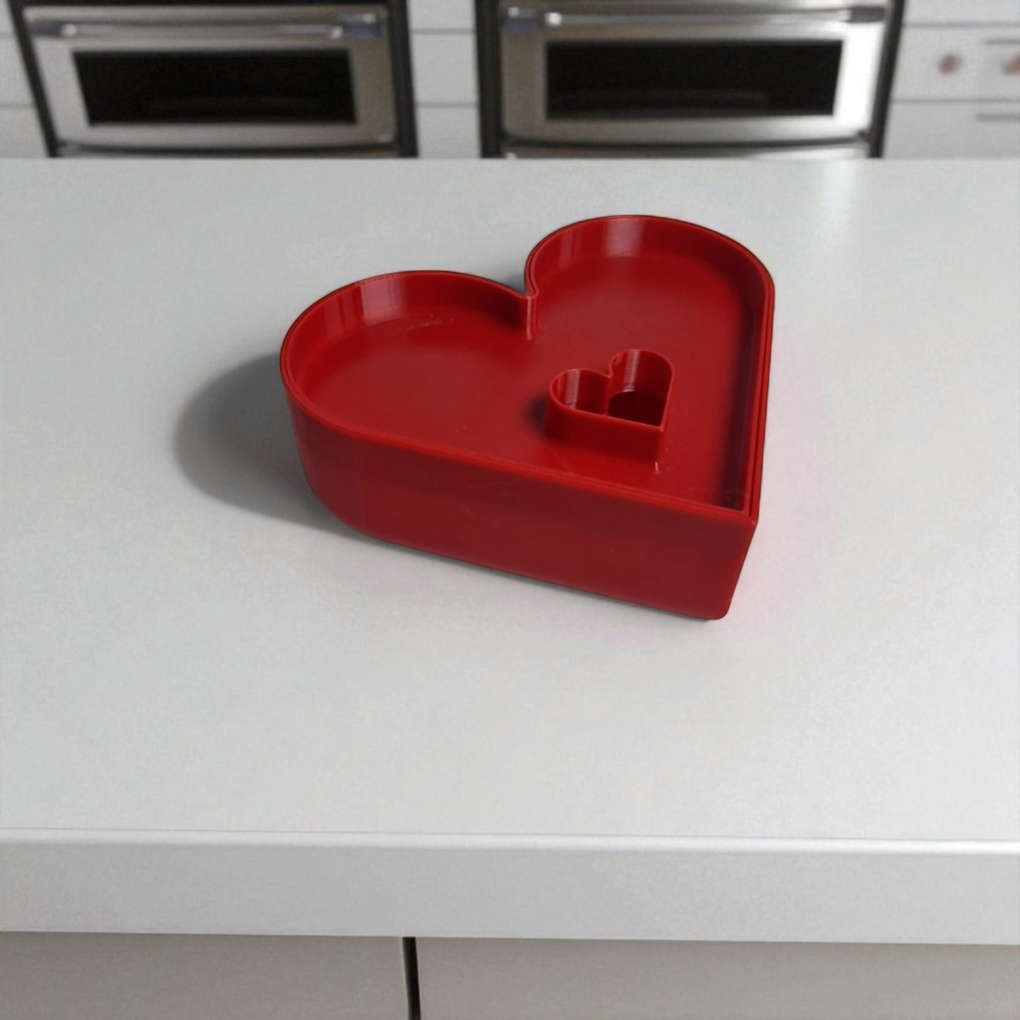 red heart-shaped tray on a white countertop with kitchen appliances in the background