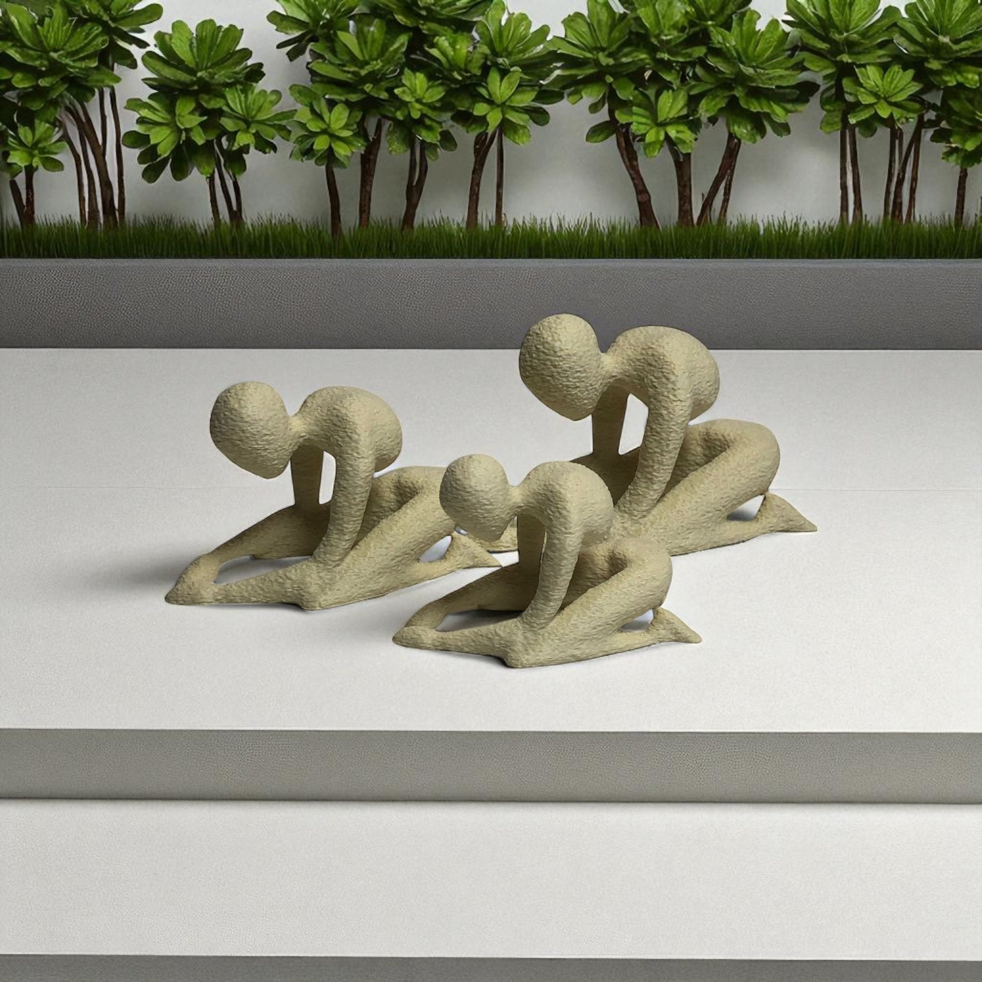 Two stone sculptures of people in a running pose on a white surface with a green forest background.