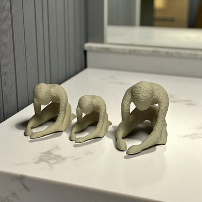 Three beige ceramic figures on a marble surface with a neutral background
