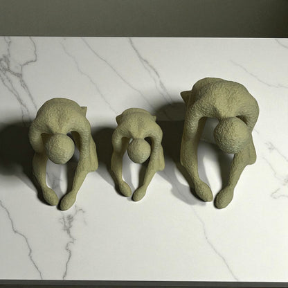 Three green ceramic sculptures of people in various poses on a marble surface