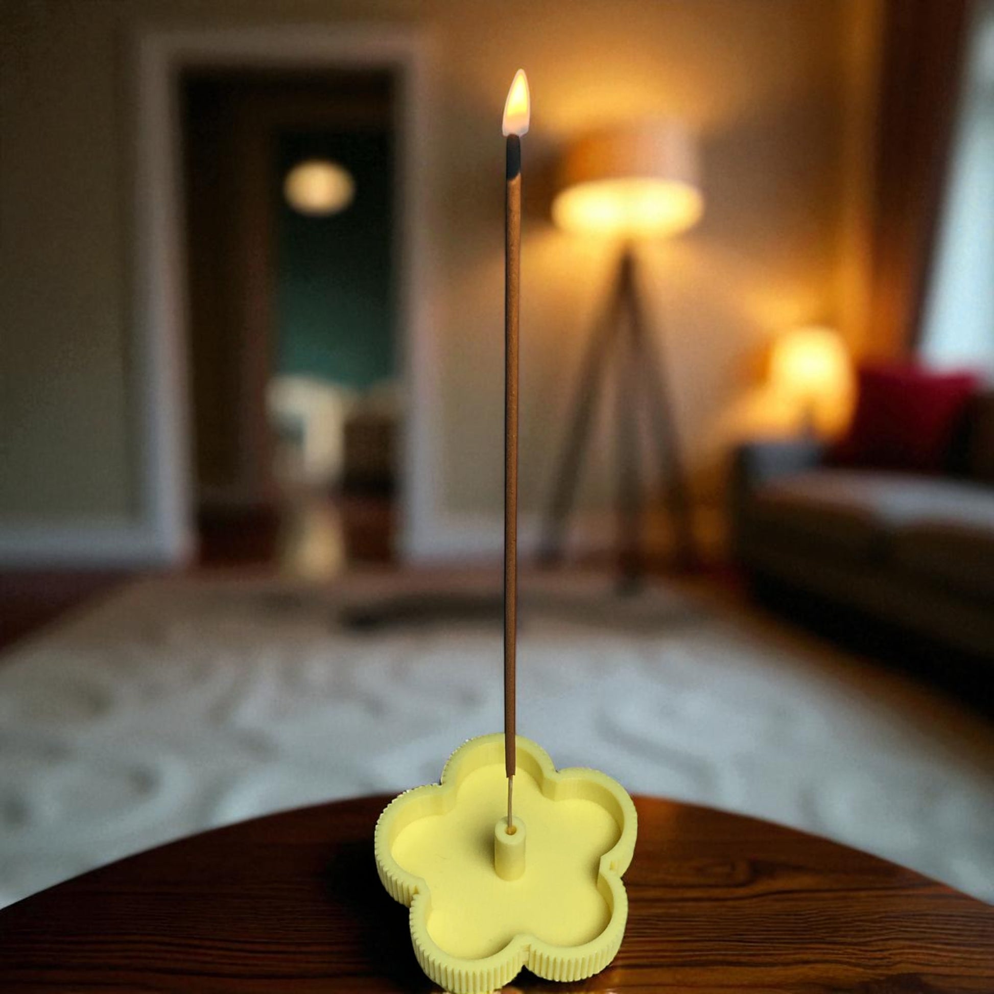 Incense stick in a yellow holder on a wooden surface with a blurred indoor background