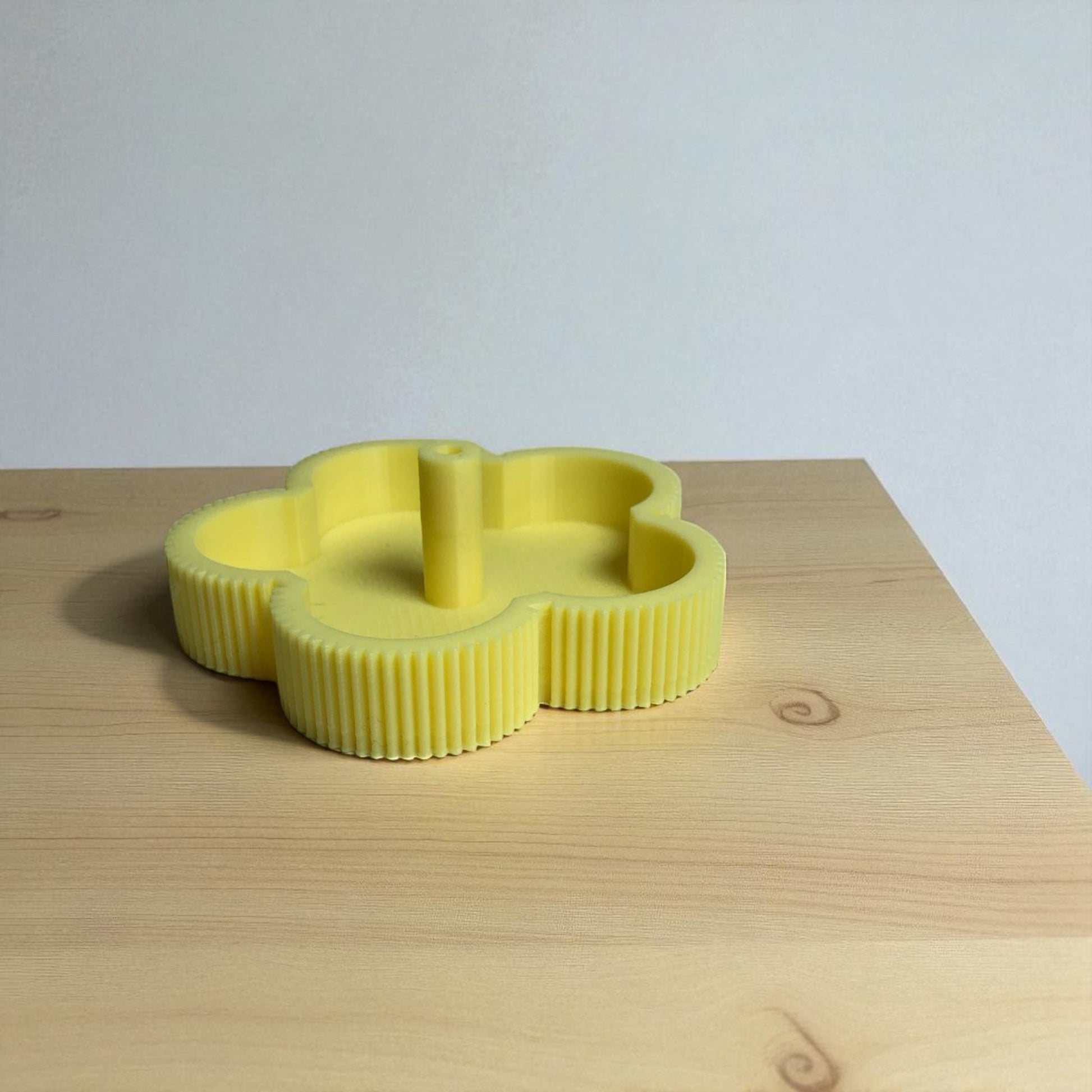 Yellow cookie cutter shaped like a cloud on a wooden surface with a light gray background