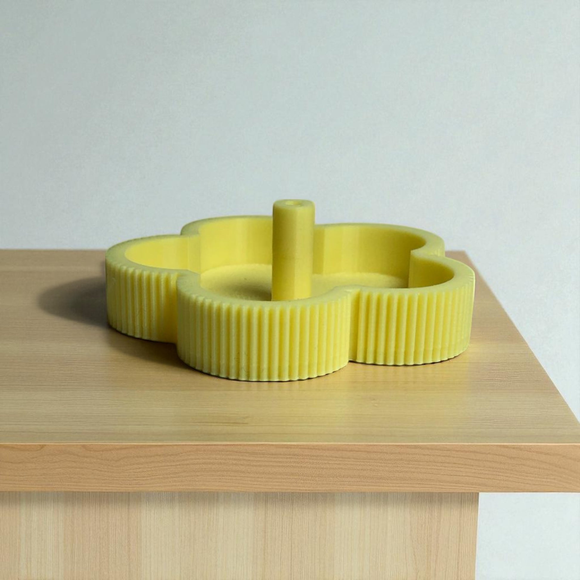 Yellow ribbed candle holder on a wooden surface with a light gray background
