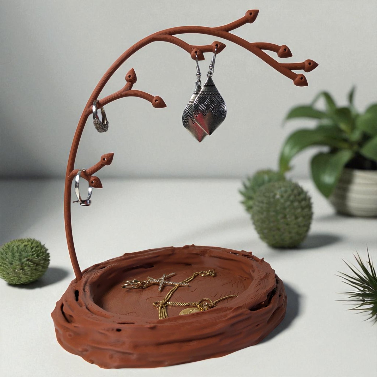 a uniquely designed bird nest jewelry tray with a branch, perfect for organizing rings, earrings, necklaces, and bracelets. the nest-shaped base includes small holes for earring storage, while the branch provides an elegant spot for hanging jewelry. made from durable, eco-friendly 3d-printed material, this nature-inspired jewelry organizer adds a stylish and functional touch to any vanity or dresser.