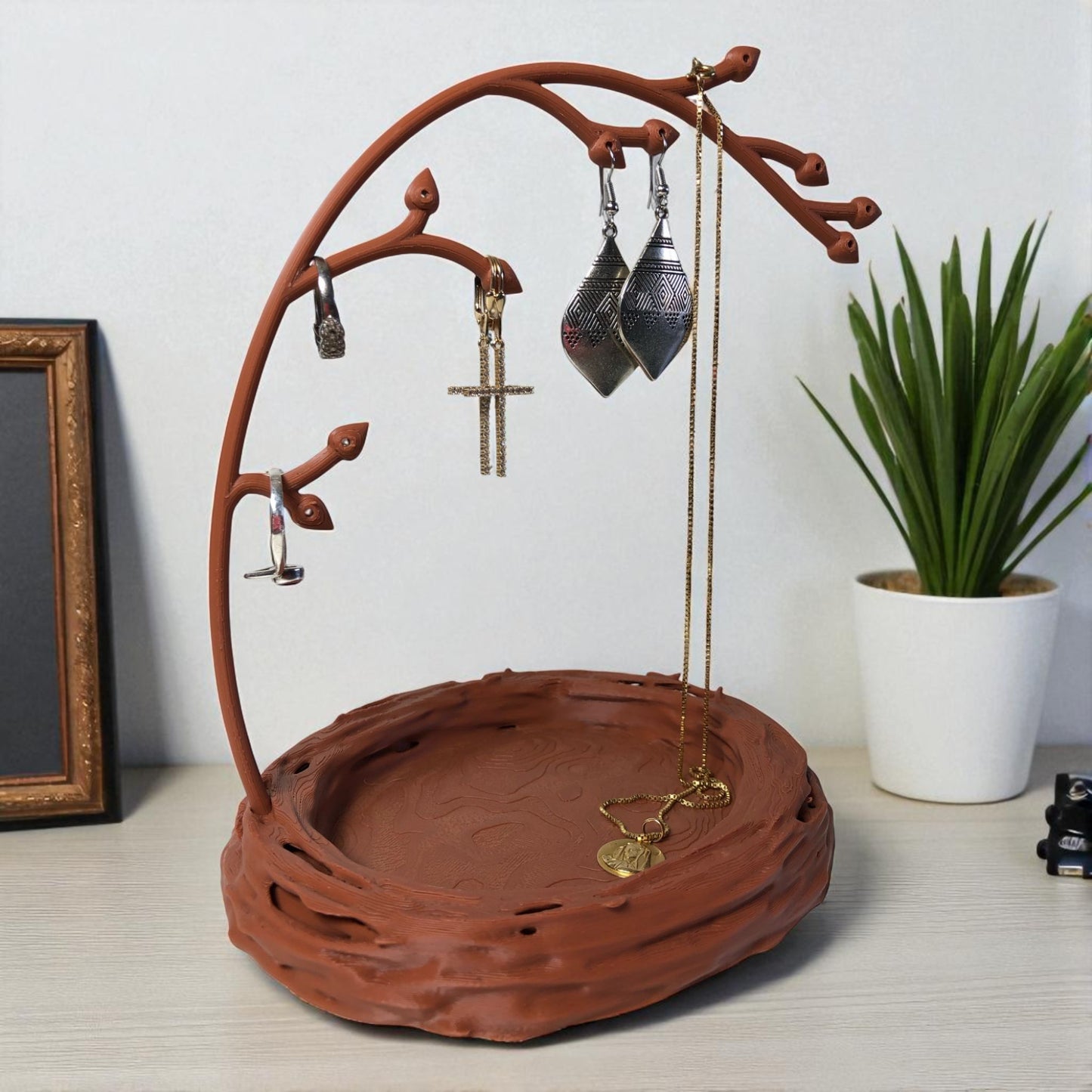 a uniquely designed bird nest jewelry tray with a branch, perfect for organizing rings, earrings, necklaces, and bracelets. the nest-shaped base includes small holes for earring storage, while the branch provides an elegant spot for hanging jewelry. made from durable, eco-friendly 3d-printed material, this nature-inspired jewelry organizer adds a stylish and functional touch to any vanity or dresser.