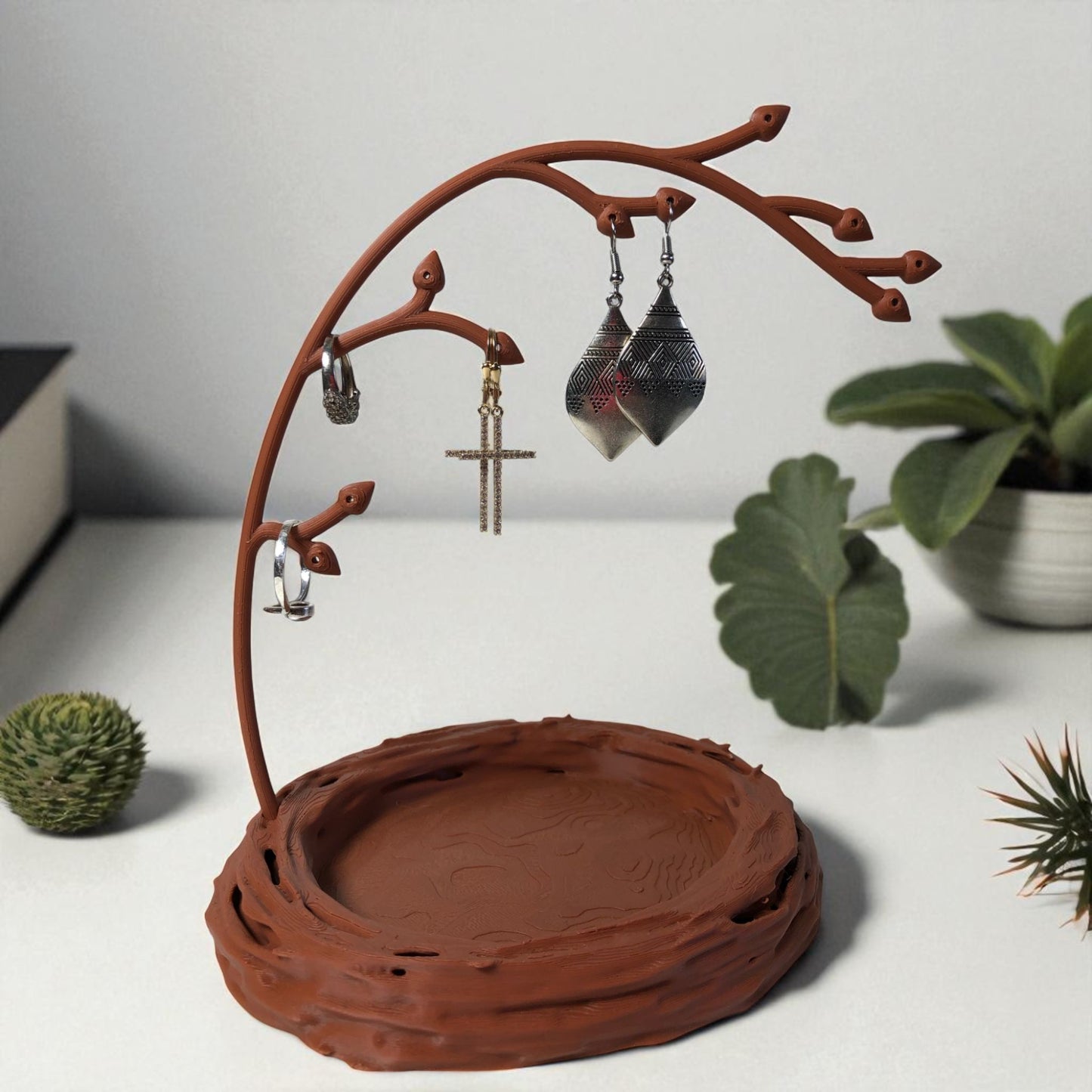 a uniquely designed bird nest jewelry tray with a branch, perfect for organizing rings, earrings, necklaces, and bracelets. the nest-shaped base includes small holes for earring storage, while the branch provides an elegant spot for hanging jewelry. made from durable, eco-friendly 3d-printed material, this nature-inspired jewelry organizer adds a stylish and functional touch to any vanity or dresser.