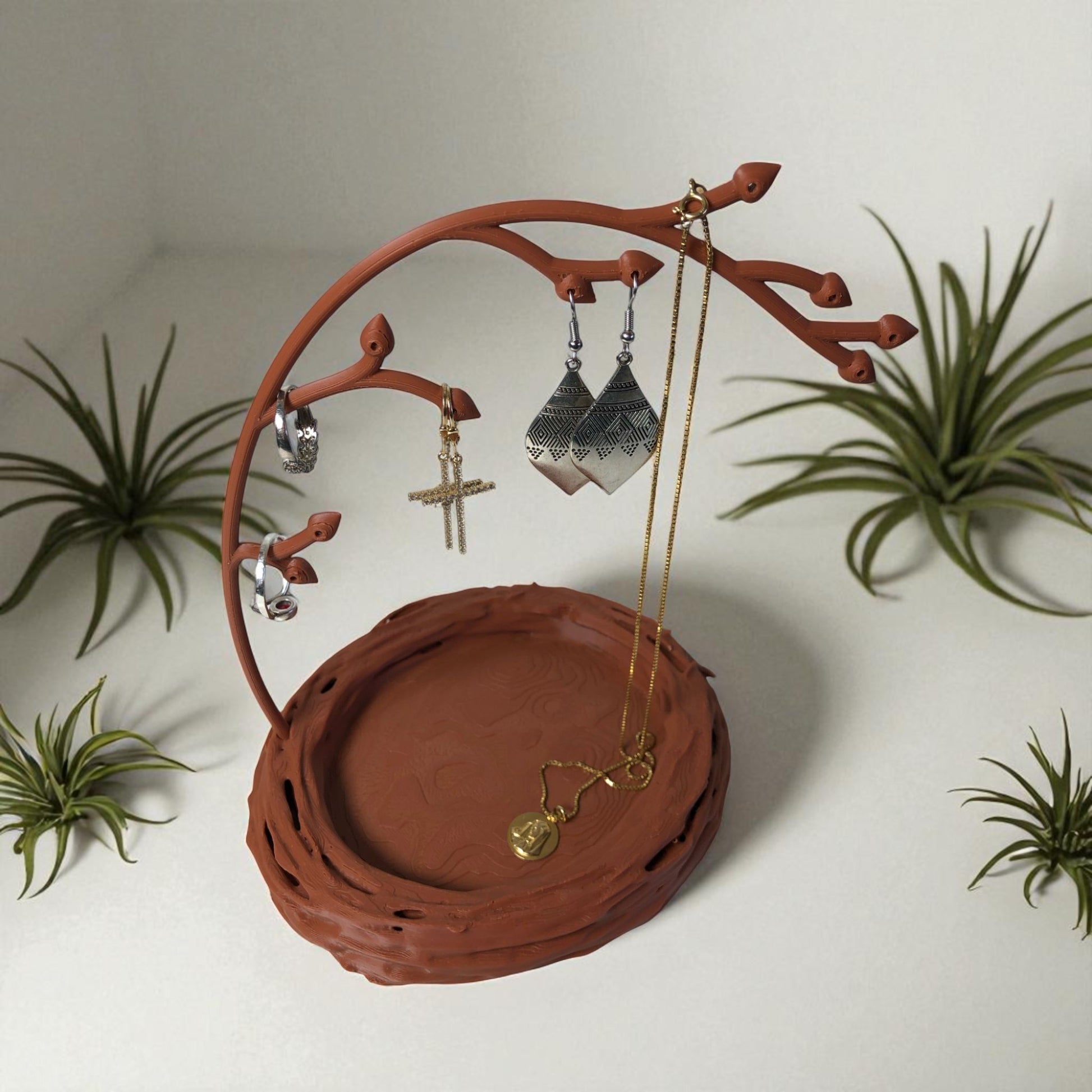 A uniquely designed bird nest jewelry tray with a branch, perfect for organizing rings, earrings, necklaces, and bracelets. The nest-shaped base includes small holes for earring storage, while the branch provides an elegant spot for hanging jewelry. Made from durable, eco-friendly 3D-printed material, this nature-inspired jewelry organizer adds a stylish and functional touch to any vanity or dresser.