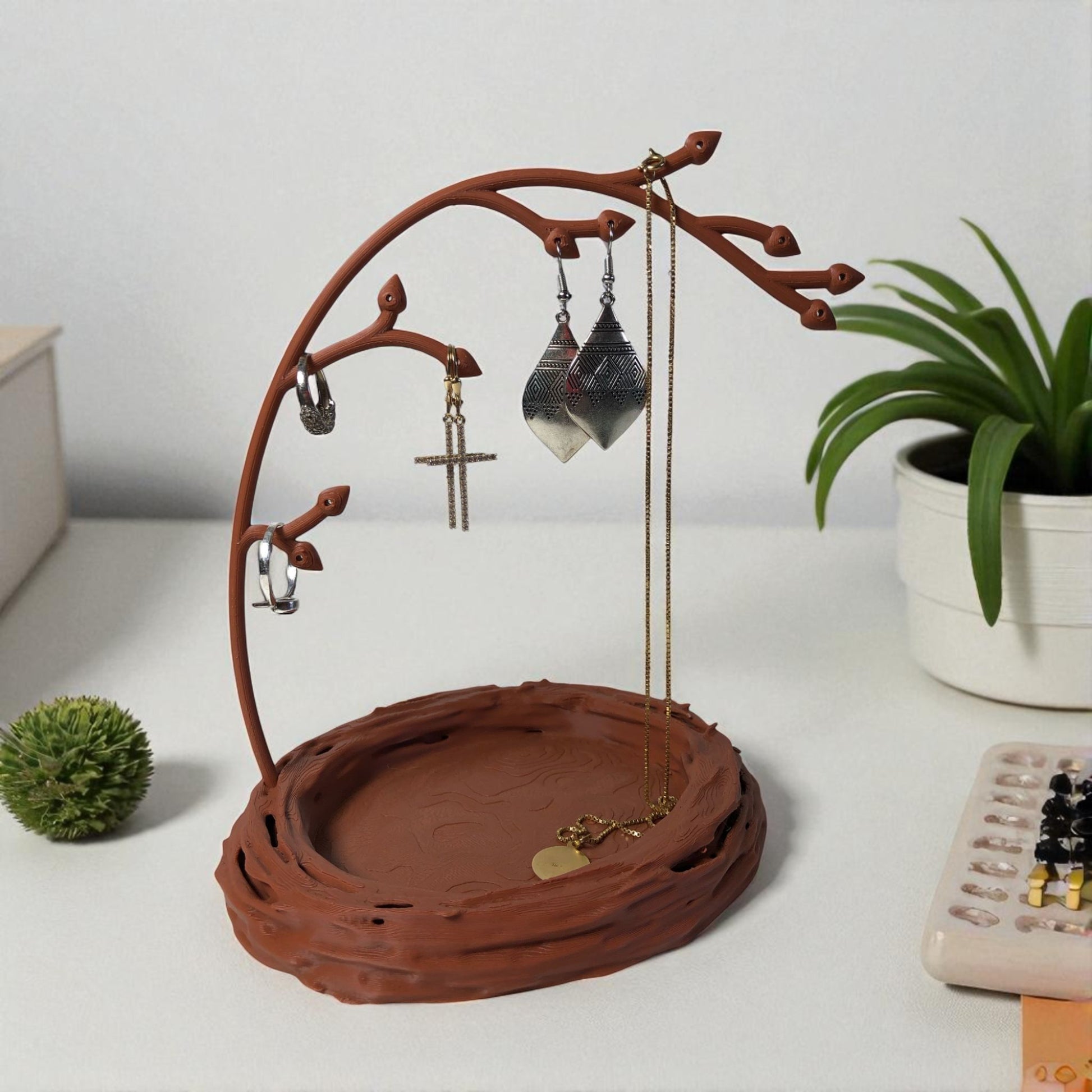 A uniquely designed bird nest jewelry tray with a branch, perfect for organizing rings, earrings, necklaces, and bracelets. The nest-shaped base includes small holes for earring storage, while the branch provides an elegant spot for hanging jewelry. Made from durable, eco-friendly 3D-printed material, this nature-inspired jewelry organizer adds a stylish and functional touch to any vanity or dresser.