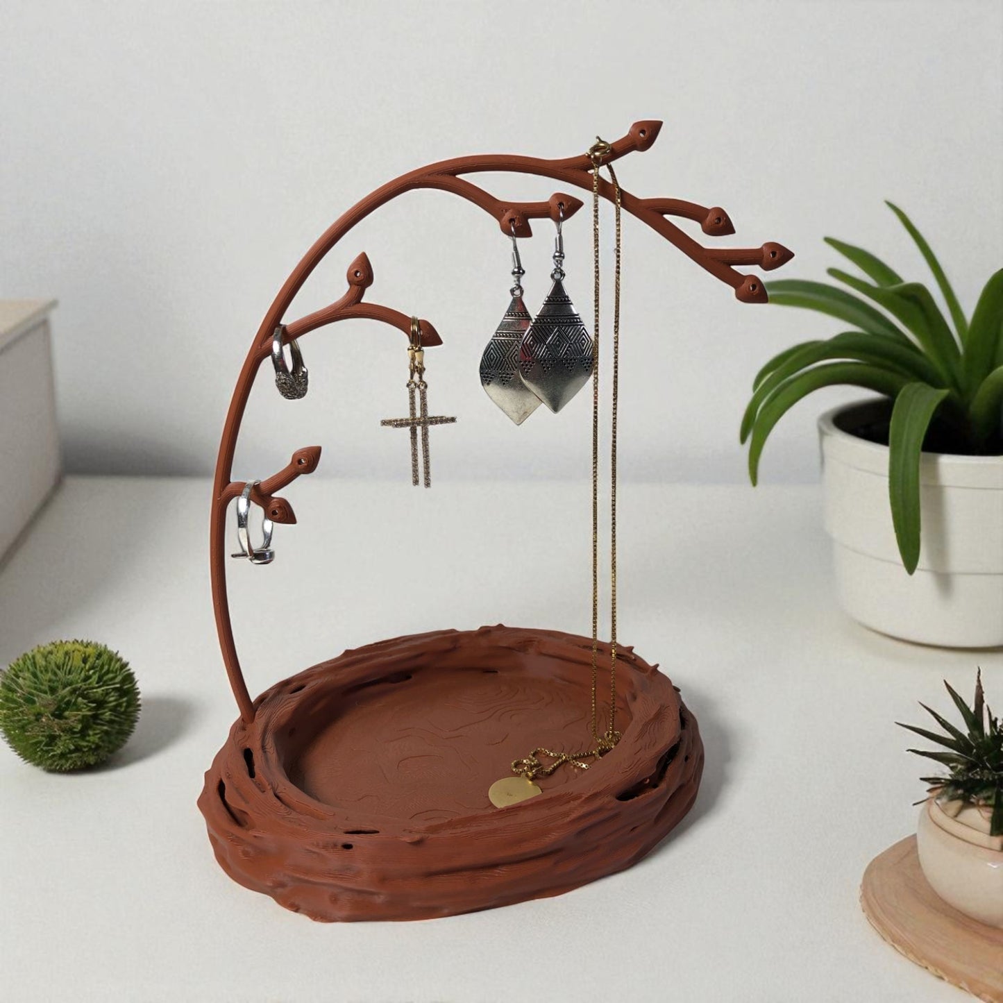 a uniquely designed bird nest jewelry tray with a branch, perfect for organizing rings, earrings, necklaces, and bracelets. the nest-shaped base includes small holes for earring storage, while the branch provides an elegant spot for hanging jewelry. made from durable, eco-friendly 3d-printed material, this nature-inspired jewelry organizer adds a stylish and functional touch to any vanity or dresser.