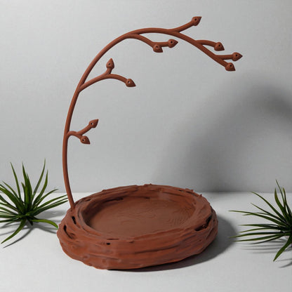 A uniquely designed bird nest jewelry tray with a branch, perfect for organizing rings, earrings, necklaces, and bracelets. The nest-shaped base includes small holes for earring storage, while the branch provides an elegant spot for hanging jewelry. Made from durable, eco-friendly 3D-printed material, this nature-inspired jewelry organizer adds a stylish and functional touch to any vanity or dresser.