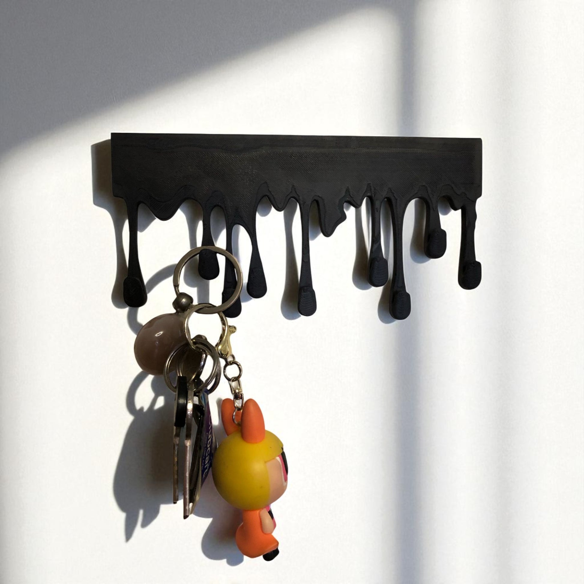 Modern Dripping Key Hanger with a unique dripping paint design, available in small (180mm x 90mm) and large (239mm x 120mm) sizes. Holds up to 9 key sets and can be mounted with adhesive strips for a rent-friendly option or secured with screws for a permanent installation. A stylish and functional wall-mounted key organizer for homes, apartments, and offices.