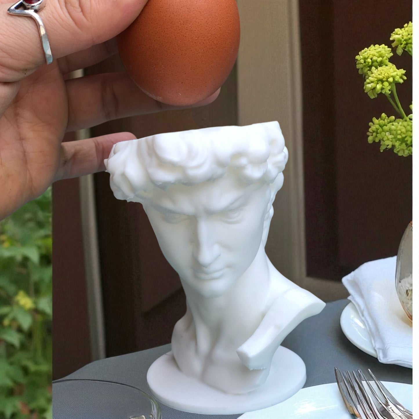 3d printed male bust egg cup in classical sculpture style, featuring a hollowed head holding a boiled egg. unique breakfast decor piece in white pla, perfect for easter table settings or artistic kitchen gifts.