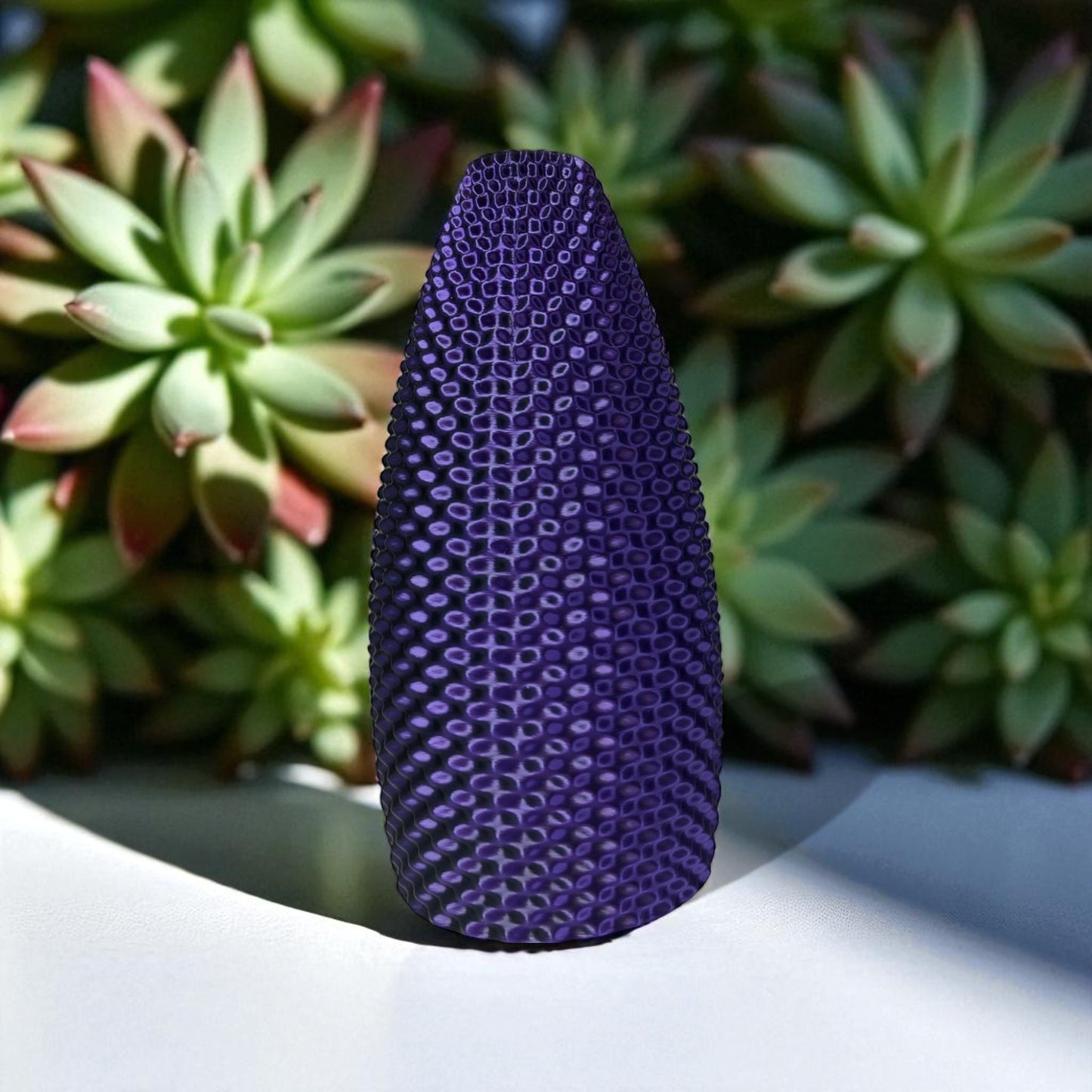 purple textured object on a white surface with succulents in the background