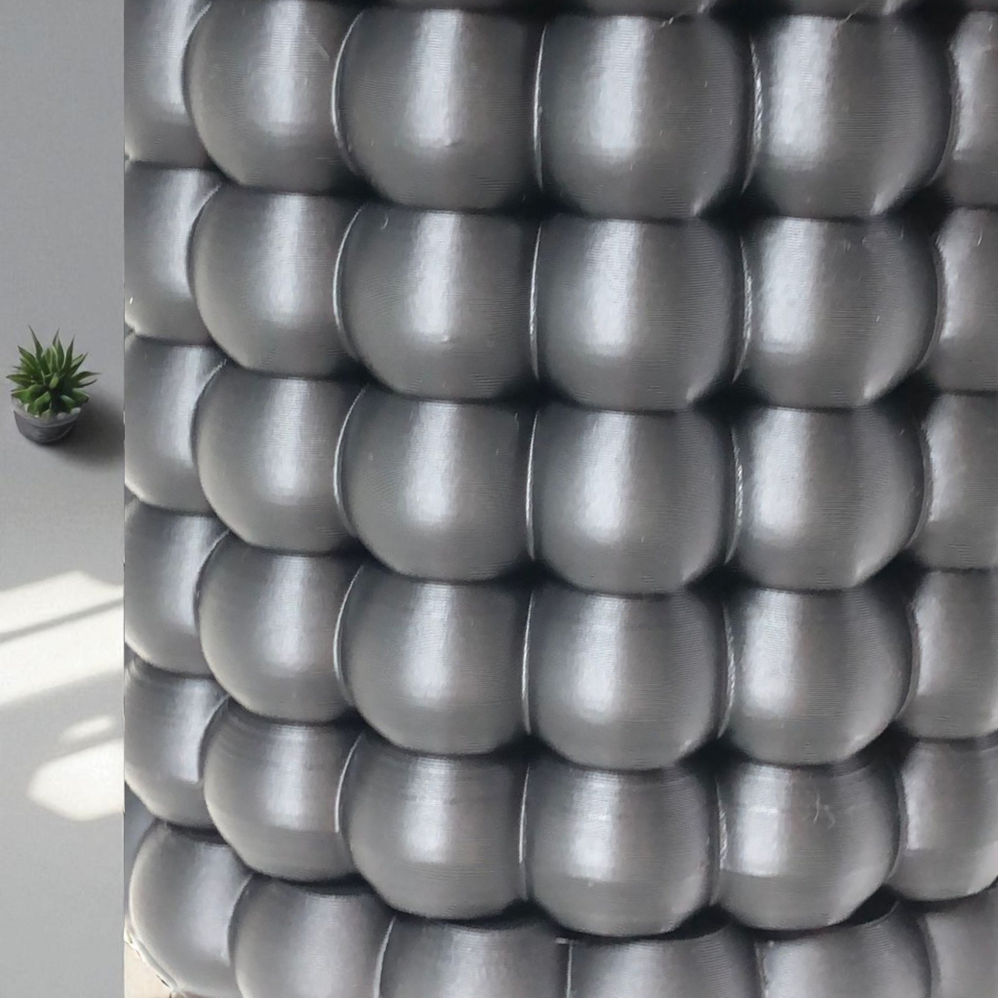 Modern black wall-mounted planter with a bubble texture design, holding a green succulent plant. Includes mounting bracket for screws or adhesive and a built-in water tray.