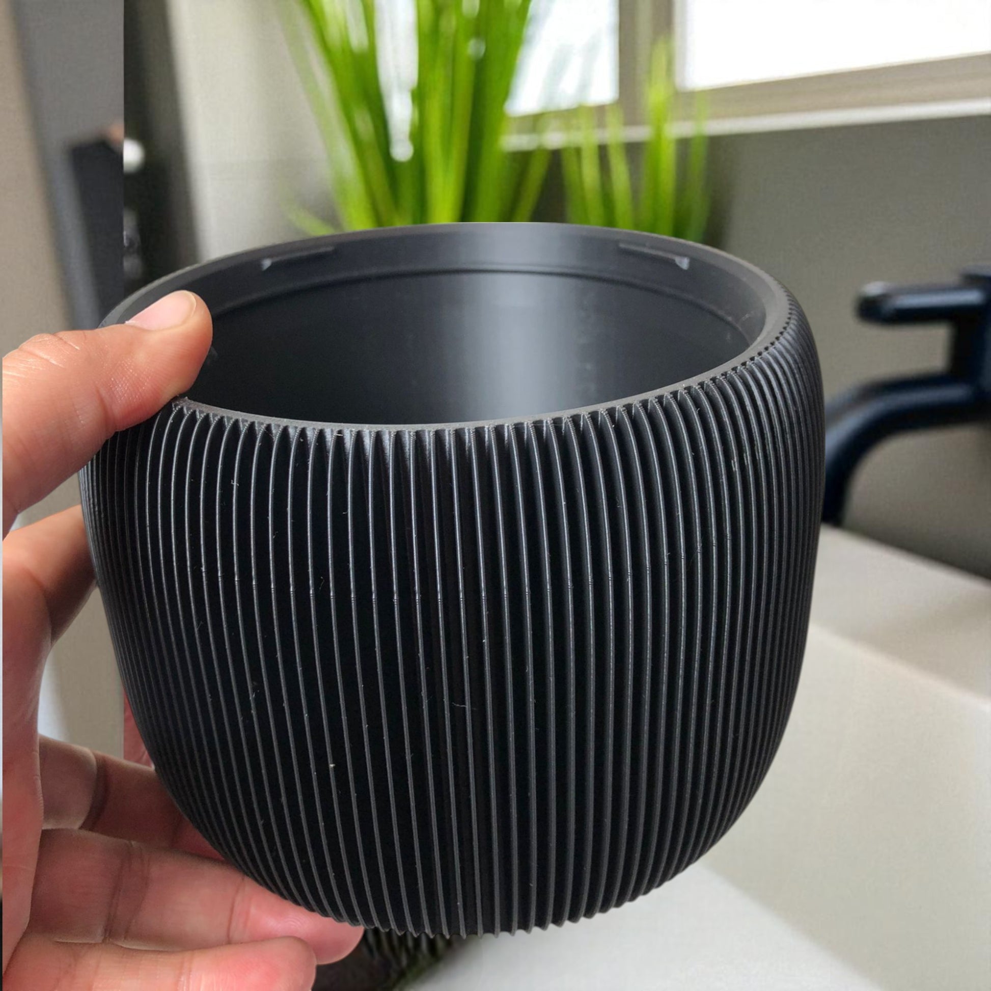 Modern black toilet paper holder with ribbed texture and lid, designed to prevent pets or children from unrolling the paper. Stylish and compact bathroom accessory shown on a white surface.