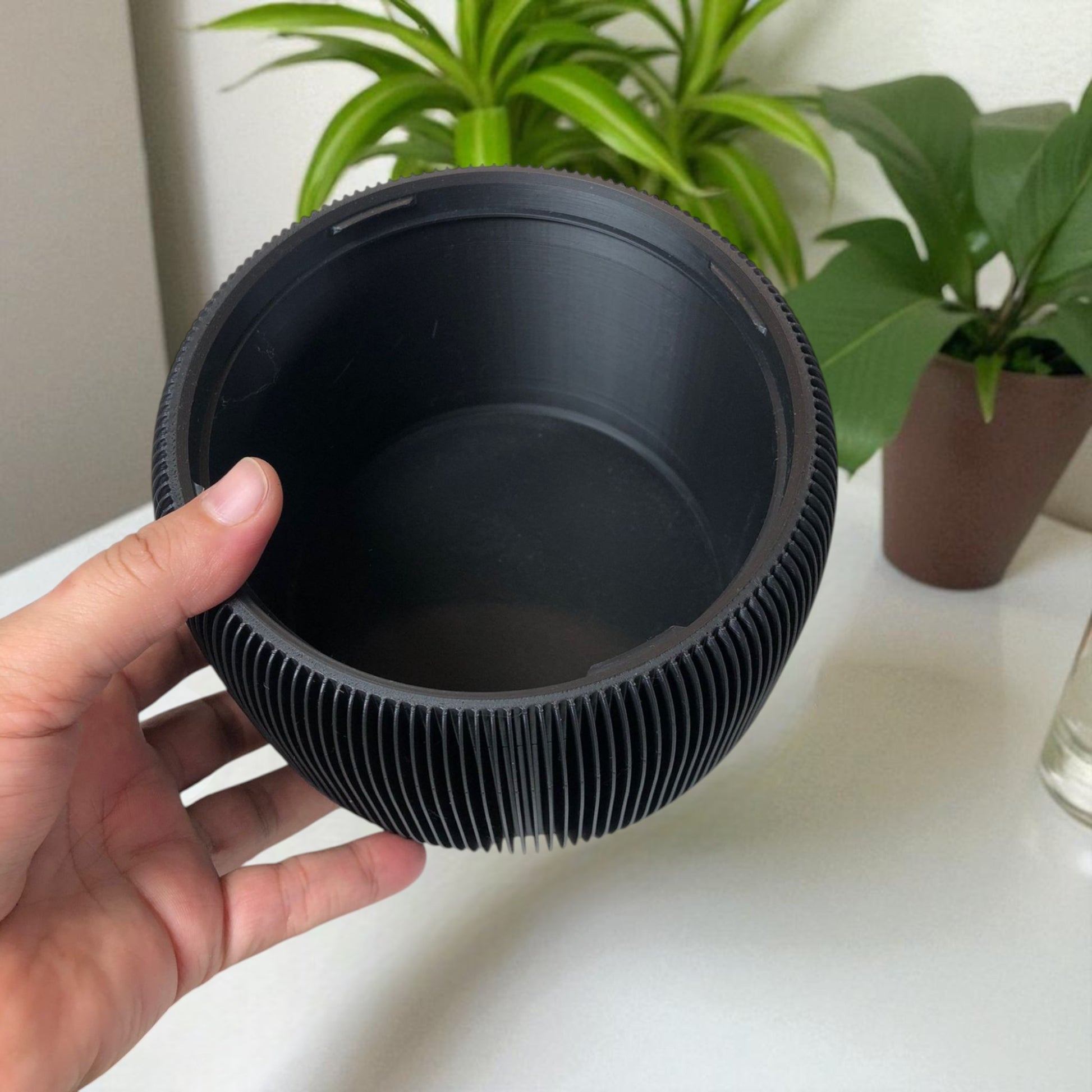 Modern black toilet paper holder with ribbed texture and lid, designed to prevent pets or children from unrolling the paper. Stylish and compact bathroom accessory shown on a white surface.