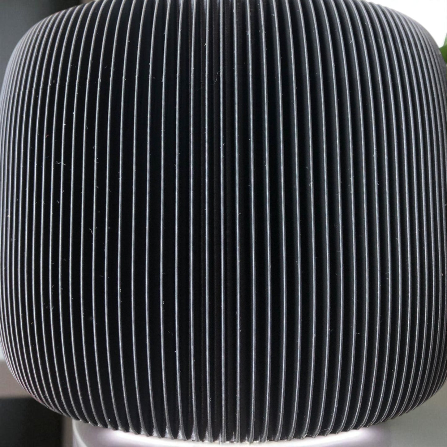 modern black toilet paper holder with ribbed texture and lid, designed to prevent pets or children from unrolling the paper. stylish and compact bathroom accessory shown on a white surface.