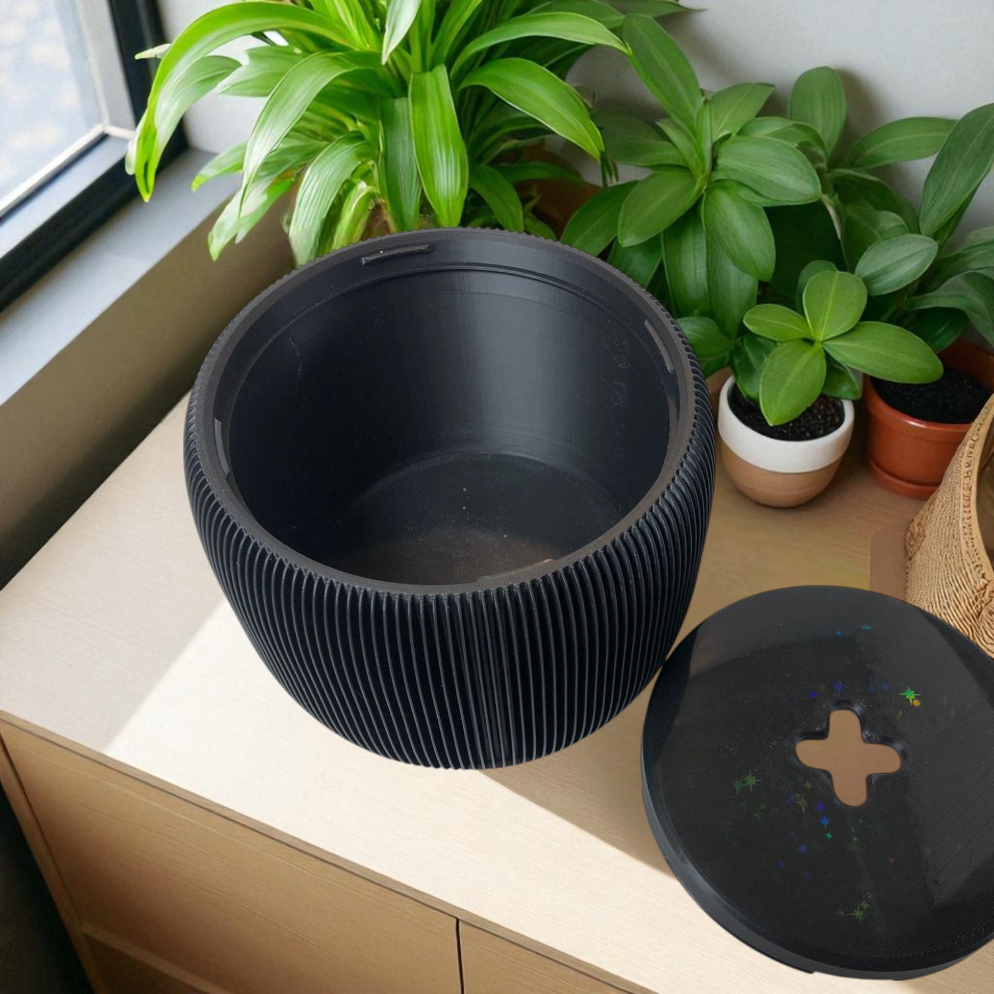 Modern black toilet paper holder with ribbed texture and lid, designed to prevent pets or children from unrolling the paper. Stylish and compact bathroom accessory shown on a white surface.