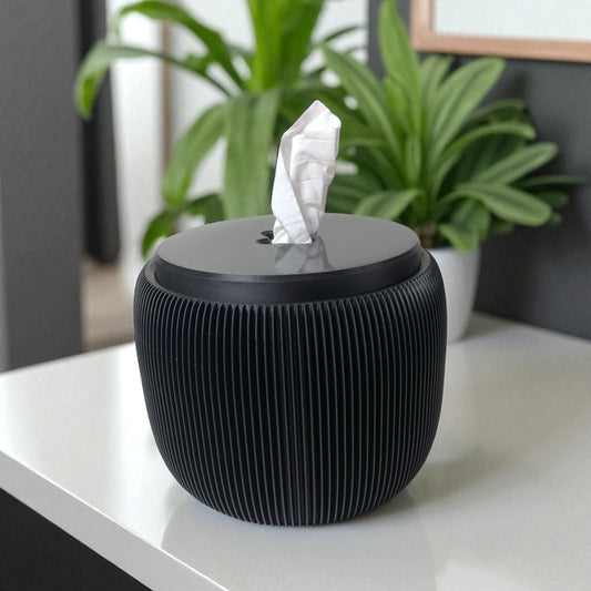 Modern black toilet paper holder with ribbed texture and lid, designed to prevent pets or children from unrolling the paper. Stylish and compact bathroom accessory shown on a white surface.