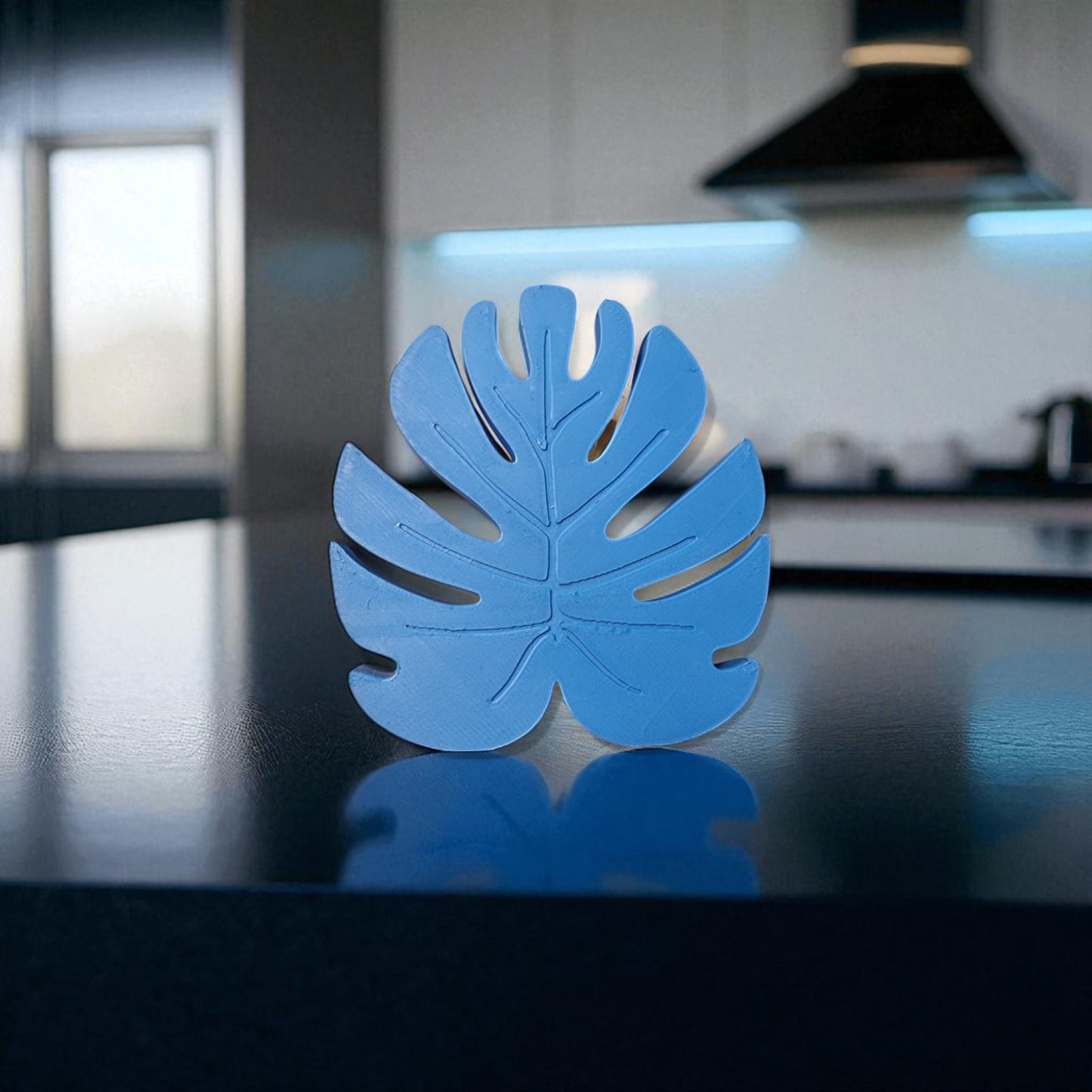 blue leaf-shaped object on a reflective surface with a blurred kitchen background