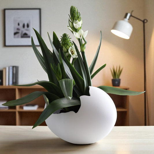 White vase with green plant on a table in a room setting