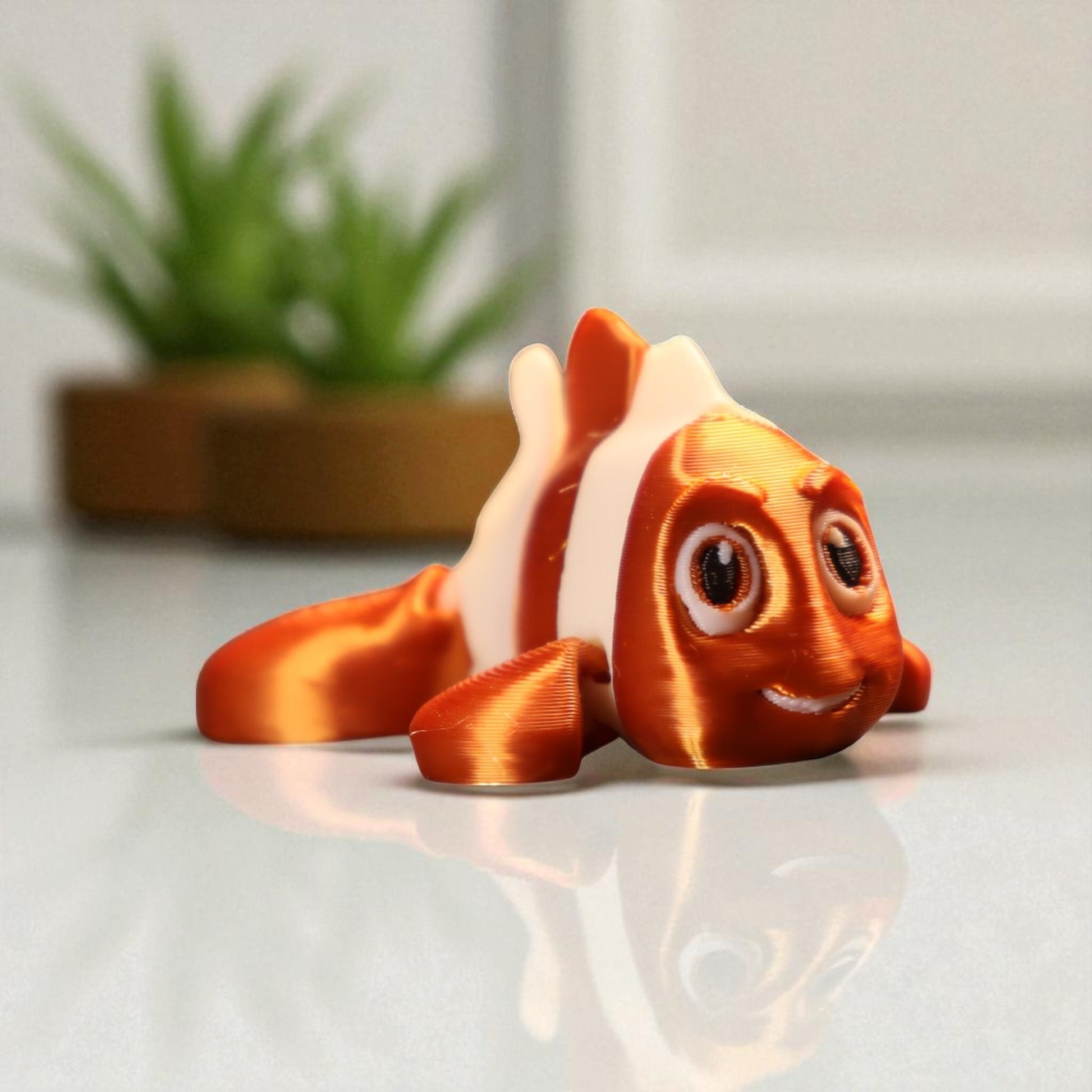 3D printed articulated clown fish toy in vibrant two-tone colors, featuring a cute face and flexible, lifelike movement, perfect as a keychain or playful ocean-themed gift.