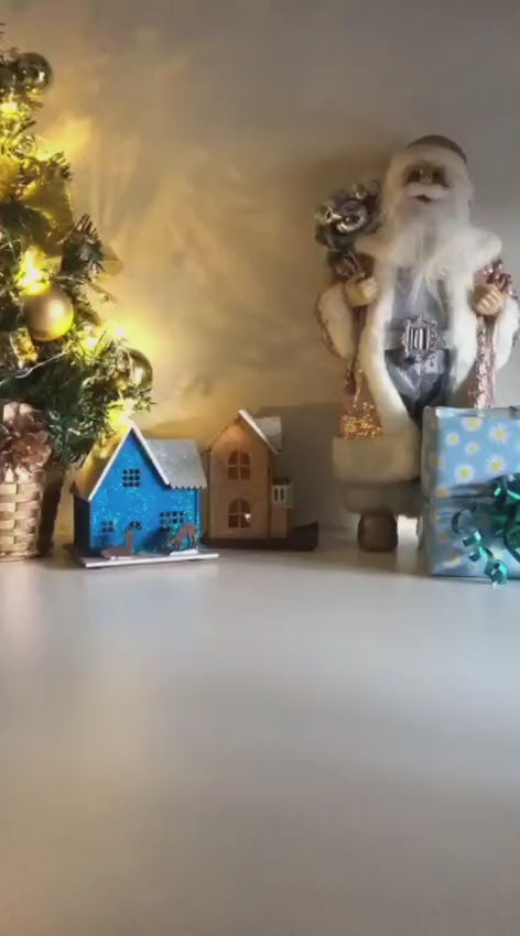 White Christmas reindeer and pine tree LED tealight decoration glowing on table, festive holiday décor for mantel or centerpiece.